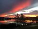 Dramatic sunset over a lake, featuring vivid red, orange, and gray colors reflecting in the calm waters at 14525 Englert Aly, Orlando, FL 32827