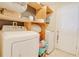 A laundry room with washer, dryer and wood shelving for organized storage at 15303 Sw 52Nd Cir, Ocala, FL 34473