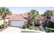 Charming single-story home with a red tile roof, tropical landscaping, and an attached two-car garage at 156 Carrera Ave, Davenport, FL 33897