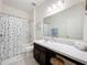 Cozy bathroom with sea-themed shower curtain, neutral tiles, and large mirror at 15865 Bradicks Ct, Clermont, FL 34711
