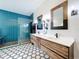 Modern bathroom with dual vanities, wood cabinets, and a striking blue tiled shower at 15865 Bradicks Ct, Clermont, FL 34711