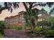 Elegant building featuring lush landscaping, mature trees and a red tile roof at 1602 Alabama Dr # Ph404, Winter Park, FL 32789