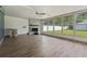 Bright sunroom with a brick fireplace, ceiling fan, wood flooring, and large windows with backyard view at 1623 Cumbie Ave, Orlando, FL 32804