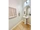 Half bathroom with pedestal sink, oval mirror, neutral tile floor, and simple decor at 16334 Saint Augustine St, Clermont, FL 34714