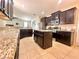 Kitchen featuring granite countertops, stainless steel appliances, dark cabinets, and a center island at 16334 Saint Augustine St, Clermont, FL 34714