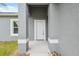 Front door view showing a well-maintained gray stucco exterior and simple landscaping at 16904 Sw 30Th Avenue Rd, Ocala, FL 34473