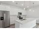 Bright kitchen boasts stainless steel refrigerator, white cabinets, and elegant pendant lighting above the island at 17139 Sw 44Th Cir, Ocala, FL 34473