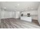 Open-concept living space with gray wood floors and a modern white kitchen with an island at 17139 Sw 44Th Cir, Ocala, FL 34473