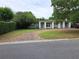 View of a well-maintained home with a brick driveway and lush landscaping, including mature trees and manicured hedges at 1773 Walnut Ave, Winter Park, FL 32789