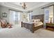 Serene main bedroom with tray ceiling, large bed, plush carpet, chandelier, and natural light from windows at 190 Osprey Hammock Trl, Sanford, FL 32771