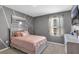 This bedroom is painted gray and pink, and features a bed, end table, and geometric artwork at 269 Ludisia Loop, Davenport, FL 33837