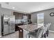 Modern kitchen featuring dark cabinetry, stainless steel appliances, and a granite-topped island with bar seating at 269 Ludisia Loop, Davenport, FL 33837