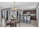 Open concept kitchen with dark cabinets, a granite island with bar seating, and an adjacent dining area with modern decor at 269 Ludisia Loop, Davenport, FL 33837