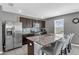 Modern kitchen featuring dark cabinetry, stainless steel appliances, and a granite-topped island with bar seating at 269 Ludisia Loop, Davenport, FL 33837