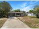 Charming single-story home featuring a carport, well-maintained lawn, and beautiful landscaping under a bright blue sky at 300 Avenue E Se, Winter Haven, FL 33880