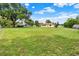 Large backyard with mature tree, lush grass, and view of the rear exterior of the home at 409 Jumper S Dr, Bushnell, FL 33513