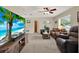 Comfortable living room with beach-themed TV, neutral carpet, ceiling fan, and large windows at 409 Jumper S Dr, Bushnell, FL 33513