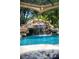 A gorgeous waterfall cascading into a swimming pool, surrounded by lush landscaping at 5950 Blakeford Dr, Windermere, FL 34786