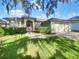 Charming single-Gathering home featuring lush landscaping, a two-car garage, and a classic red front door at 704 Pickfair Ter, Lake Mary, FL 32746