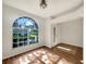 Sunny living room featuring hardwood floors, a large arched window, and fresh, clean interior design at 704 Pickfair Ter, Lake Mary, FL 32746