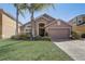 Charming home featuring a well-manicured lawn, mature palm trees, and an attached two-car garage at 927 Orange Cosmos Blvd, Davenport, FL 33837