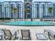 Community pool area featuring comfortable lounge chairs with luxury condos in the background at 100 S Eola Dr # 611, Orlando, FL 32801