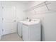 Bright laundry room with tile floor features a modern washer, dryer, and overhead shelving at 1120 Saguaro St, Haines City, FL 33844