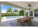 Covered patio with a wooden dining table overlooking a serene pool and garden at 11707 Hampstead St, Windermere, FL 34786