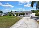 Classic single-story home with a gray roof, a large driveway, and landscaped shrubbery at 1216 Floral Way, Apopka, FL 32703