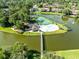 Overhead view of a community pool and tennis court nestled on an island within a lake at 140 Deer Lake Cir, Ormond Beach, FL 32174
