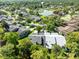 Scenic aerial view of a community with lush greenery, pond, and residences with dark gray rooftops at 140 Deer Lake Cir, Ormond Beach, FL 32174
