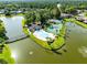 Aerial view of a community pool, tennis courts, and clubhouse on an island within a lake at 140 Deer Lake Cir, Ormond Beach, FL 32174