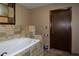 Bathroom features an oversized tub with tiled walls, door, and travertine floors at 1508 Lake Mills Rd, Chuluota, FL 32766