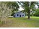 Quaint gray home featuring a metal roof, verdant lawn, and mature trees draped with Spanish moss at 1508 Lake Mills Rd, Chuluota, FL 32766