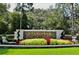 Landscaped community entrance sign featuring decorative brick, flowering shrubs, manicured bushes, and mature shade trees at 1716 Wild Indigo Ter, Oviedo, FL 32766