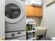Efficient laundry room with stacked washer and dryer, utility sink, storage shelves, and wall cabinets for organization at 1716 Wild Indigo Ter, Oviedo, FL 32766
