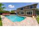 Inviting backyard pool with slide, brick patio, and manicured lawn adjacent to the two-story tan home with white framed windows at 1716 Wild Indigo Ter, Oviedo, FL 32766