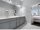 Elegant bathroom features double sinks, granite countertops, tile flooring and an open view to the primary bedroom at 17200 Gathering Place Cir, Clermont, FL 34711