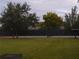 Tennis court with a black fence, and a lush green lawn in the foreground at 2408 Swailes Dr # 6, Orlando, FL 32837