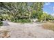 Gravel driveway with trees and landscaping leading to detached buildings and sheds at 2418 W 1St St, Sanford, FL 32771
