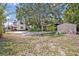 Spacious front yard with mature trees, storage sheds, and gravel area at 2418 W 1St St, Sanford, FL 32771