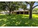Large backyard with mature trees and a grassy area for activities at 24720 Calusa Blvd, Eustis, FL 32736