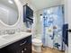 Charming bathroom featuring vanity sink, tiled shower with floral curtain, and neutral decor at 27143 Nostalgia Dr, Leesburg, FL 34748