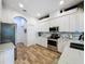 Modern kitchen featuring stainless steel appliances, granite countertops, white cabinets, and wood-look floors at 27143 Nostalgia Dr, Leesburg, FL 34748