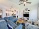 Open-concept living room with blue sofa, ceiling fan, and view of the modern kitchen with breakfast bar at 27143 Nostalgia Dr, Leesburg, FL 34748