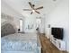 Well-lit main bedroom with hardwood floors, ceiling fan, and connecting hallway to other areas of the home at 27143 Nostalgia Dr, Leesburg, FL 34748