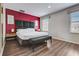 Bright bedroom with a bed, bench, accent wall, and wood-look flooring at 3019 White Orchid Rd, Kissimmee, FL 34747