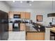 Modern kitchen equipped with black appliances, wood cabinets, and generous granite countertop space at 3019 White Orchid Rd, Kissimmee, FL 34747