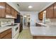 Kitchen featuring wood cabinets, white appliances, and stone countertops at 3121 Thistlehill Drive, Winter Park, FL 32792