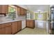 Kitchen featuring wood cabinets, white appliances, stone countertops and views into the sunroom at 3121 Thistlehill Drive, Winter Park, FL 32792